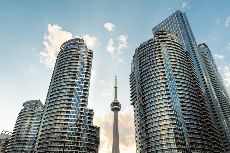 Tall modern condo buildings on both sides of CN Tower rising in middle.